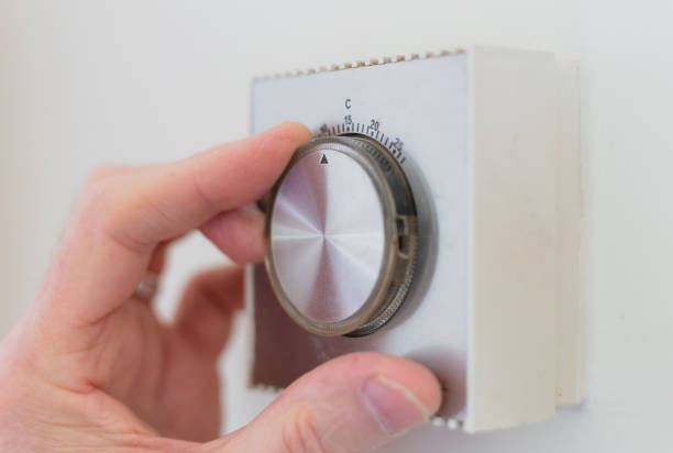 istock Hand adjusting thermostat - reducing energy consumption 1383440981