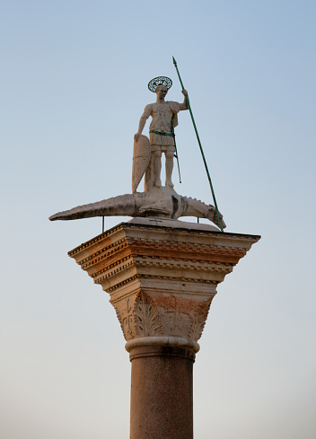 Dawn light shines on the statue of Saint Theodore with a crocodile at the Piazza San Marco, Venice, Italy
