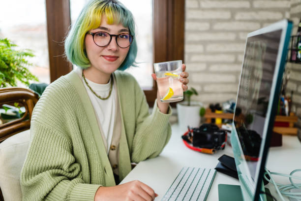 młoda kobieta pije wodę podczas pracy - blue hair zdjęcia i obrazy z banku zdjęć