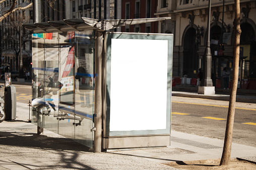 A bus stop in a city with a blank billboard