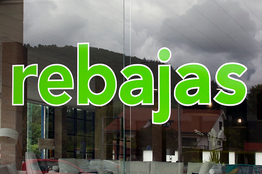 Santiago de Compostela, Spain- July 7, 2021: Sales green sign close-up view on window store in Galicia, Spain.