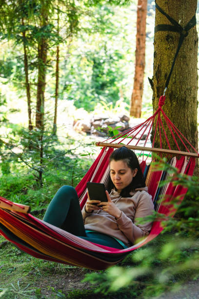istock woman laying down in hammock reading book 1383464064