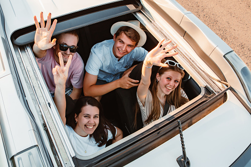 group of friends in car looking up through sunroof
