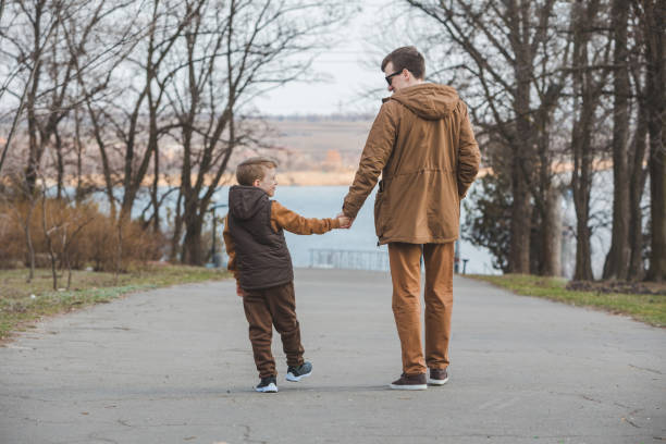 istock father with son walking by park holding hands 1383464114
