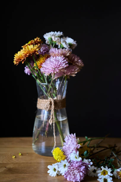 istock fresh daisy flowers and glass vase on table 1383464416