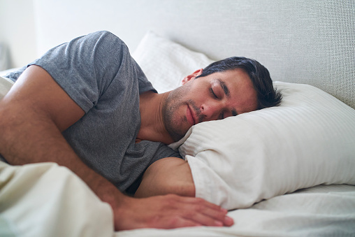Portrait of hispanic adult man sleeping in bed during daytime