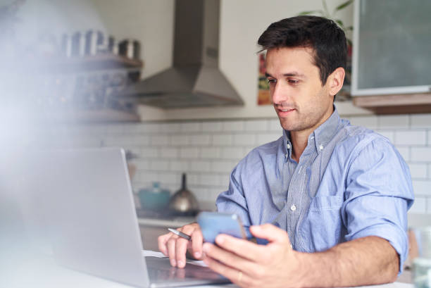 istock Young adult hispanic entrepreneur using laptop while sitting in kitchen 1383470173