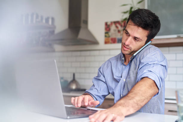 istock Young adult hispanic man talking on smart phone while working from home 1383470283