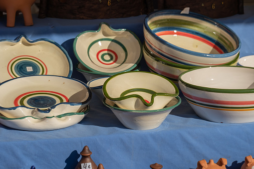 Collection of colorful ceramic pottery, plates and bowls are local craft products from Spain. Ceramic plates display in a fair stall. Colorful of vintage ceramic plates.