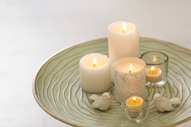 istock Beautiful burning candles on tray against light background 1383470693