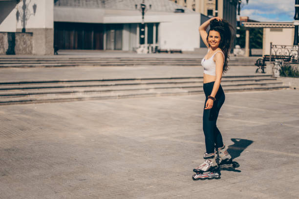 Young brunette woman is rollerblading on a city square