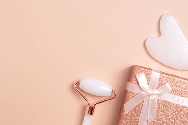 istock Beautiful composition of face roller, guasha and gift box on beige background. Gift concept. Creative trendy cosmetics flat lay with copy space 1383473250
