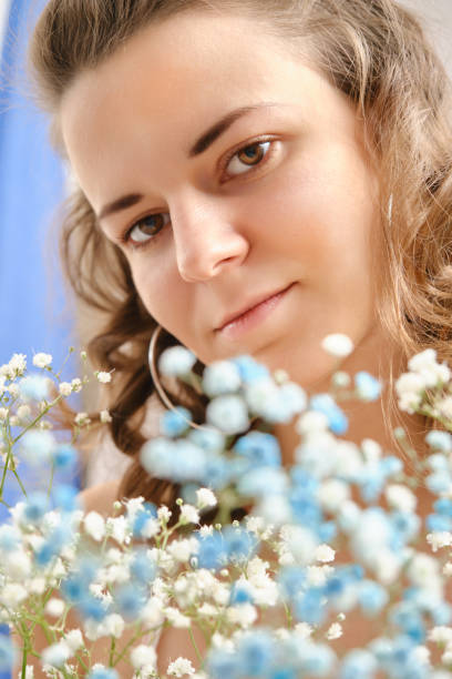 young happy woman in dress posing with flowers smiling