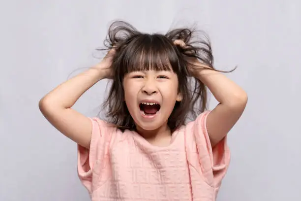 Photo of Angry Asian girl on white background, angry child, frantic gesture expression and put his hand on his head.