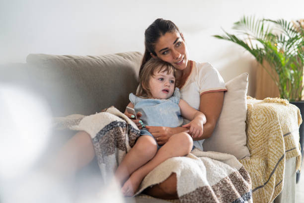istock Young mother watching tv with toddler while sitting on sofa 1383474495