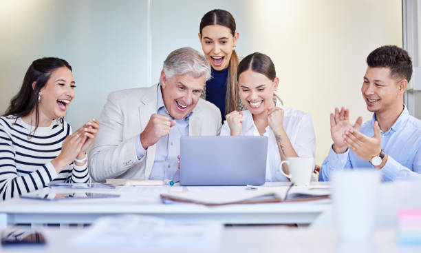 istock Shot of a group of businesspeople cheering while using a laptop at work 1383474499