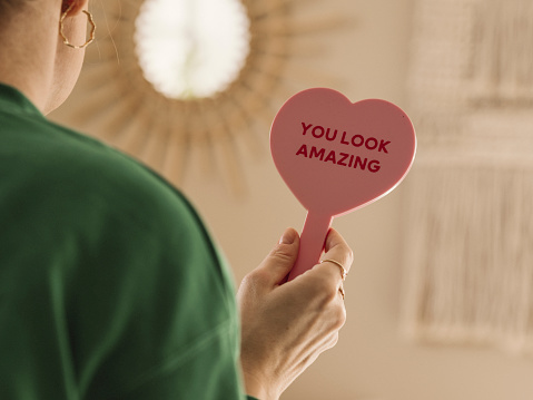 Woman holding you look amazing on heart sign 
Compliment flatter
Photo taken indoors at home unrecognizable person