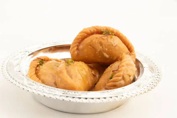 Photo of Indian Mithai Gujia Also Called Gujiya, Pirukiya, Pirukia, Pedakiya, Karanji, Basundi Gughra Made Of Suji Ghee Stuffed With Mawa Khoya Chasni Mava Khoa Is Enjoyed On Deepawali, Teez, Holi And Teej