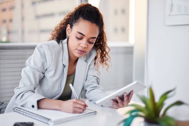 istock A young businesswoman writes notes in a notebook from her digital tablet 1383475317