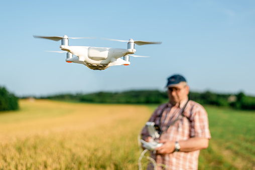 Mature Man Farmer Pilot Using Drone Remote Controller