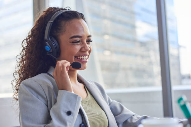 istock A young agent holds the headset microphone and smiles- skyscraper background 1383478384