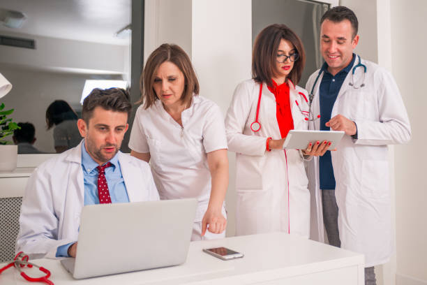 istock Group team of doctors standing and discussing while looking at a pc, laptop. 1383479253