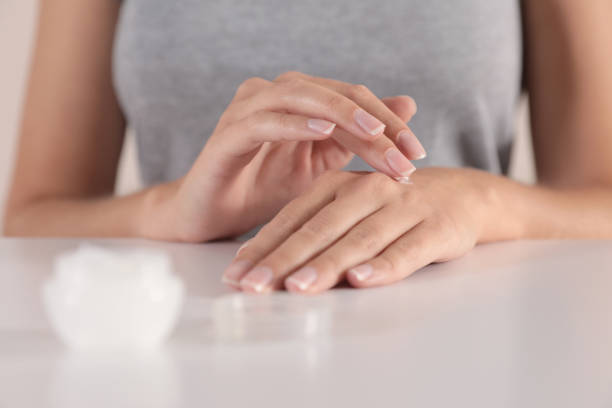 istock Young woman applying hand cream at table, closeup 1383480412