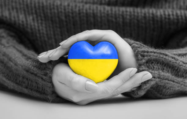 las manos de las mujeres sostienen un corazón con los colores de la bandera ucraniana. rezar por ucrania - ukraine war fotografías e imágenes de stock
