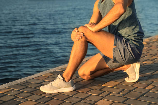 istock Man in sportswear having knee problems near river at sunset, closeup 1383481923