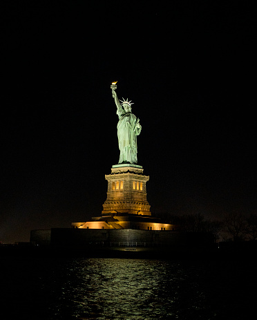 The Statue of Liberty in New York on Liberty Island lit up by spotlights in the evening