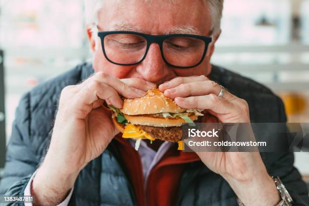 Senior Man Eating Burger In Fast Food Restaurant Stock Photo - Download Image Now - Eating, Senior Adult, Burger