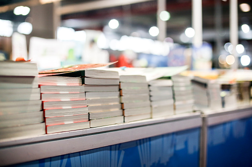 Large group of books stacked on a fair stall.