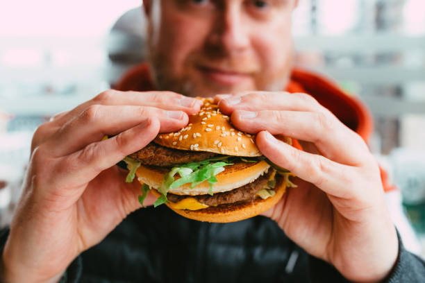 istock Man eating cheeseburger in fast food restaurant 1383489942