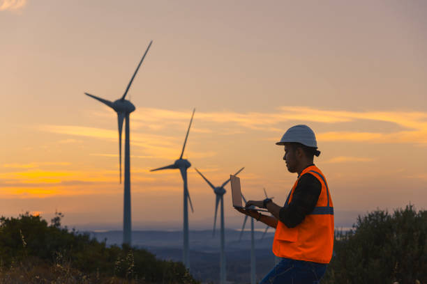 istock Young maintenance engineer man working in wind turbine farm at sunset. 1383489944