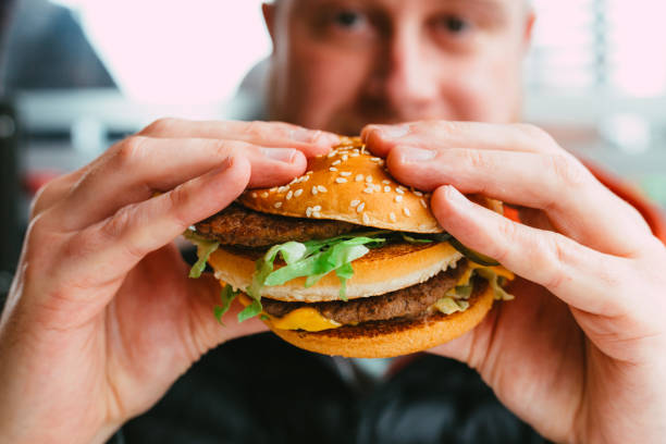 istock Man eating cheeseburger in fast food restaurant 1383489945
