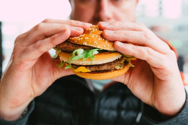 istock Man eating cheeseburger in fast food restaurant 1383489962