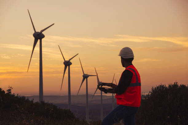 istock Young maintenance engineer man working in wind turbine farm at sunset. 1383490779