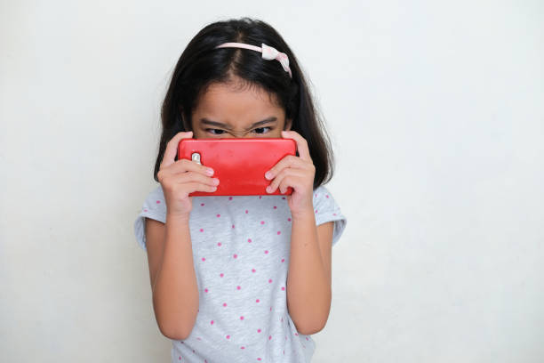 Asian kid playing mobile games with very close distance Asian kid playing mobile games with very close distance keluarga stock pictures, royalty-free photos & images