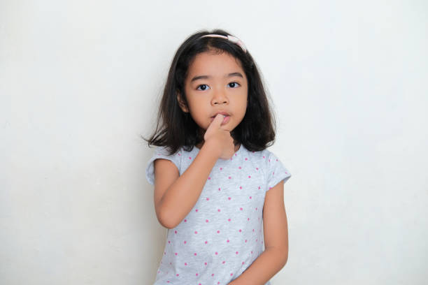 istock Asian kid bitting her thumb finger nail. Bad habit concept 1383493085
