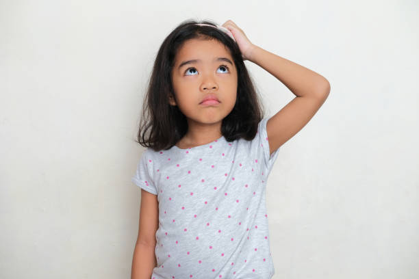 istock Asian kid scratching her head with eyes looking up showing confused expression 1383493105