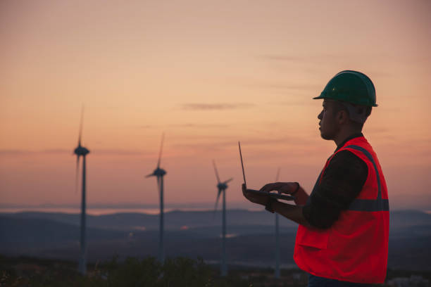 istock Young maintenance engineer man working in wind turbine farm at sunset. 1383493521