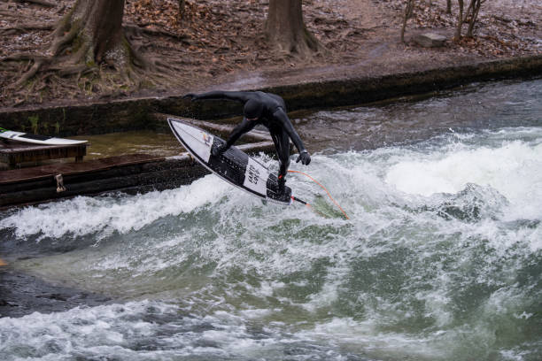 Munich, Germany - Jun 04, 2024: Surfer in the city river, Munich is famous for people surfing in urban enviroment called Eisbach