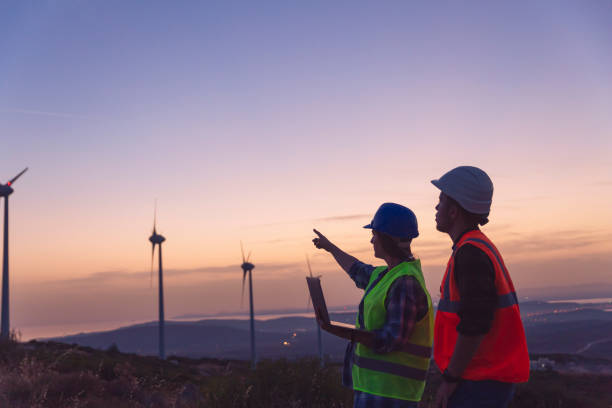 istock Young maintenance engineer team working in wind turbine farm at sunset. 1383494687