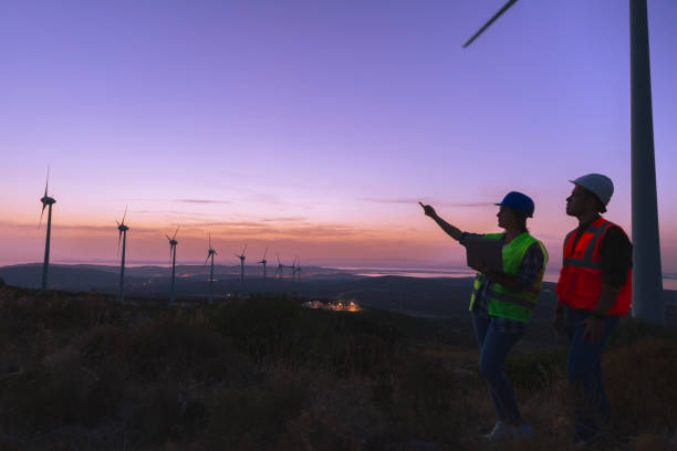 istock Young maintenance engineer team working in wind turbine farm at sunset. 1383494692