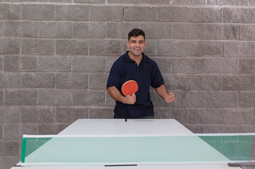 Portrait of a male business executive cheerfully celebrating a win during a table tennis match at a leisure room