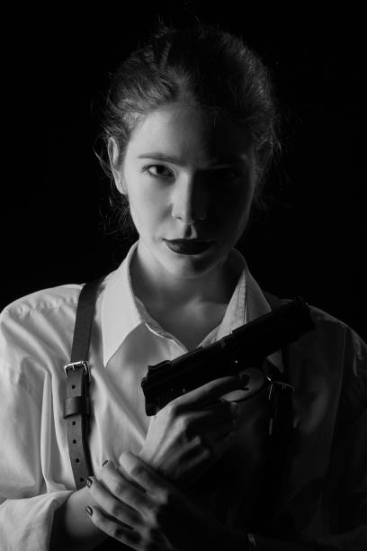serious young woman with gun in dark looking at camera monochrome image