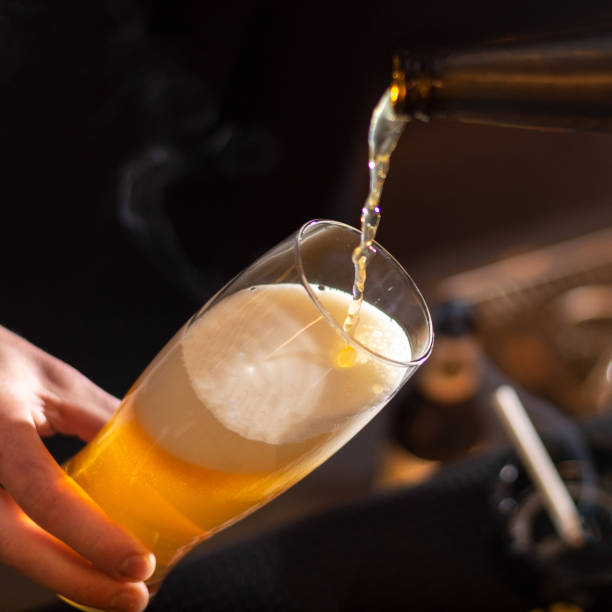istock bartender pour beer to the glass from bottle 1383505684