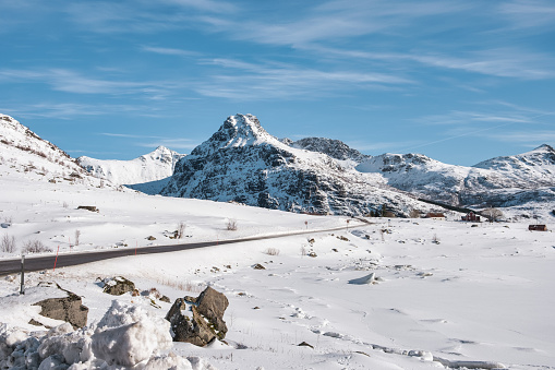 View of snowy mountain range and the road in winter on sunny day at Lofoten islands, Norway