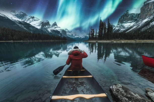 magnifiques aurores boréales sur l’île de l’esprit avec un voyageur masculin en canoë au parc national jasper - jasper national park photos et images de collection