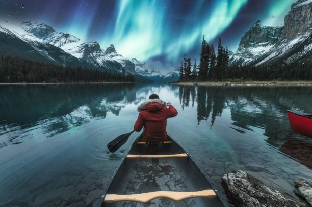 Beautiful aurora borealis over spirit island with male traveler on canoe at Jasper national park Beautiful aurora borealis over spirit island with male traveler on canoe at Jasper national park, AB, Canada canadian rockies photos stock pictures, royalty-free photos & images